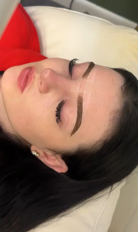 Client lying back with brows tinted, waxed and mapped with a measuring string