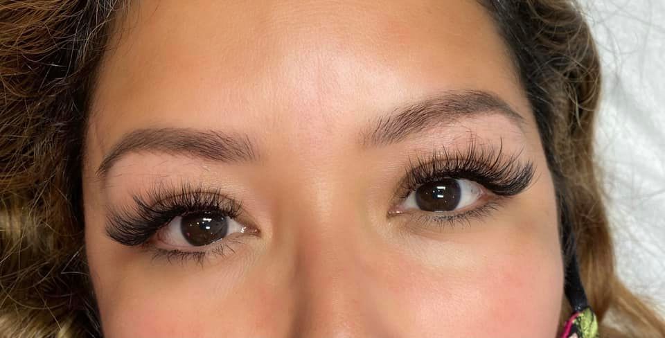 A close-up of a person's face showcasing eyelash extensions on both eyes, with defined and voluminous lashes, done by a skilled Lakeland lash artist.